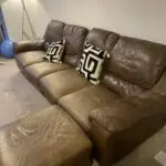 Brown leather sofa with recliner seat and footstool