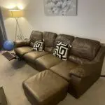 Brown leather sofa with recliner seat and footstool