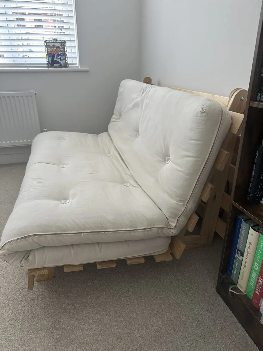 2 person Futon style sofa bed. Wooden frame and cream fabric cushion.