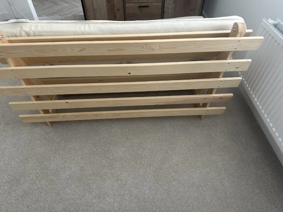 2 person Futon style sofa bed. Wooden frame and cream fabric cushion.