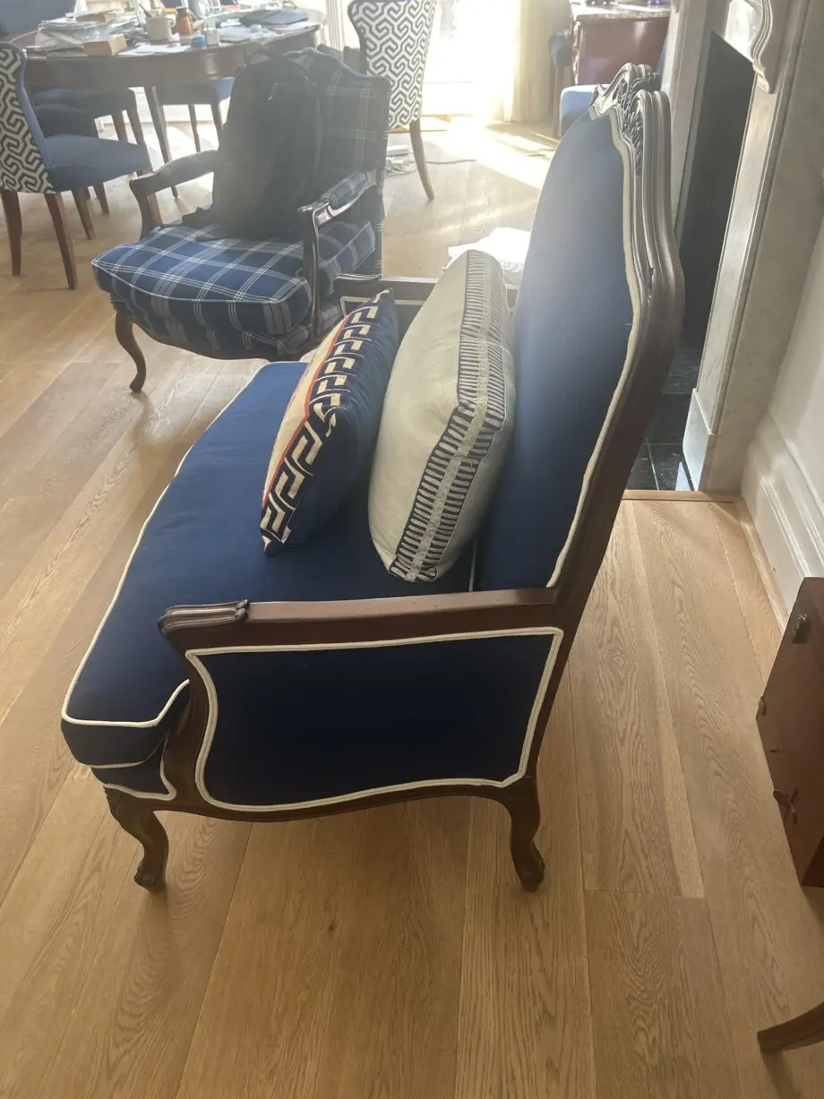 Blue loveseat with white piping