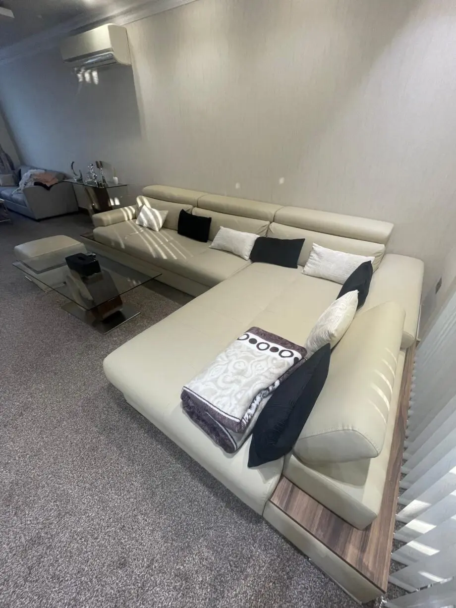 Modern beige/cream leather corner sofa with matching ottoman/footstool.