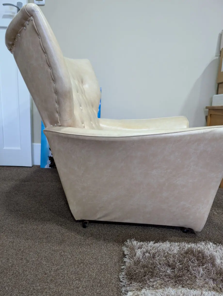 A pair of cream vinyl winged backed button arm chairs,