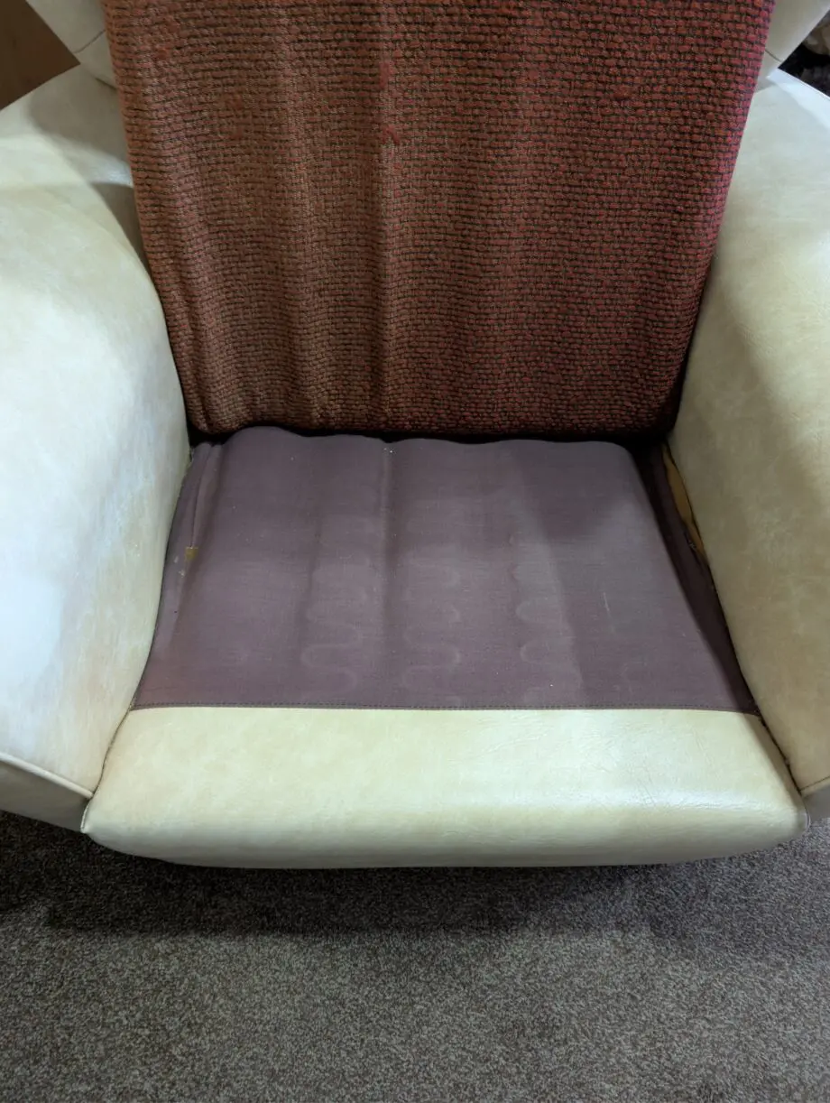 A pair of cream vinyl winged backed button arm chairs,