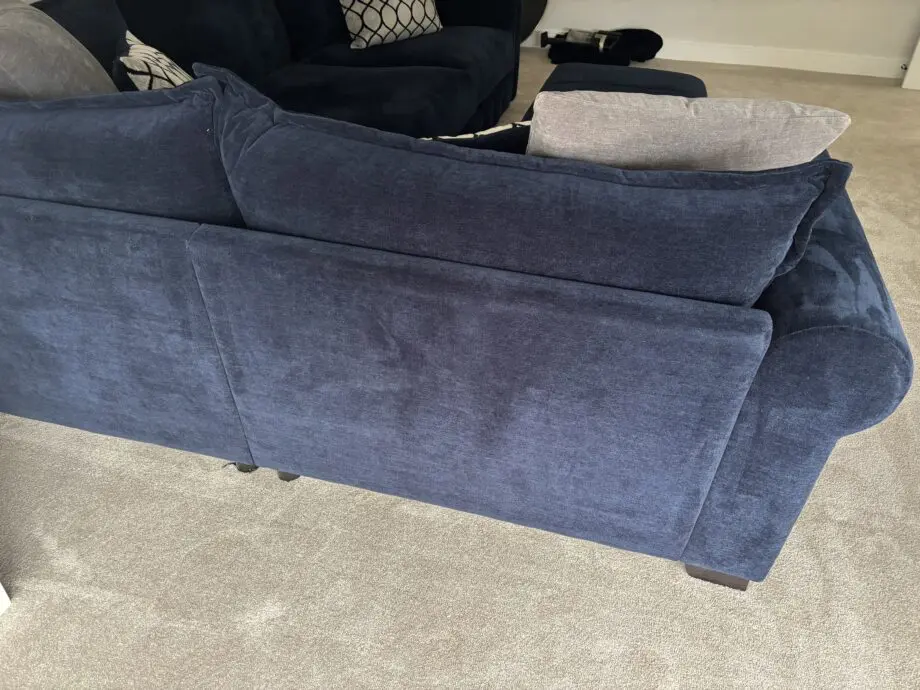 Large left hand corner sofa from Furniture Village. Navy blue with navy and grey scatter cushions included. Black feet. Matching footstool