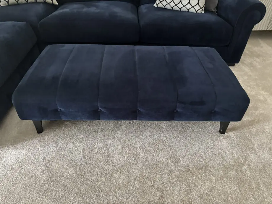 Large left hand corner sofa from Furniture Village. Navy blue with navy and grey scatter cushions included. Black feet. Matching footstool