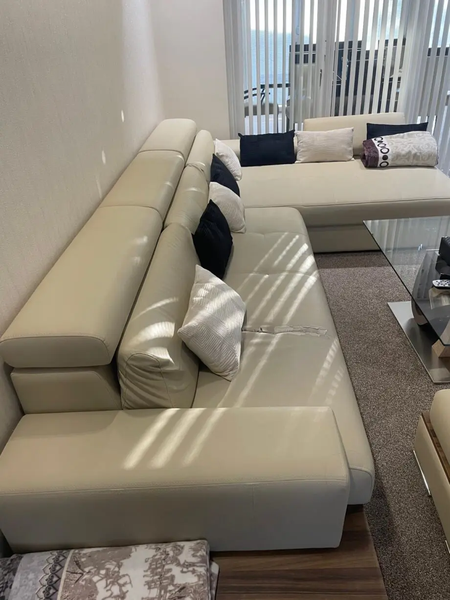 Modern beige/cream leather corner sofa with matching ottoman/footstool.
