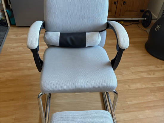 Chair with padded arms and silver metal base with footrest sponge in light grey