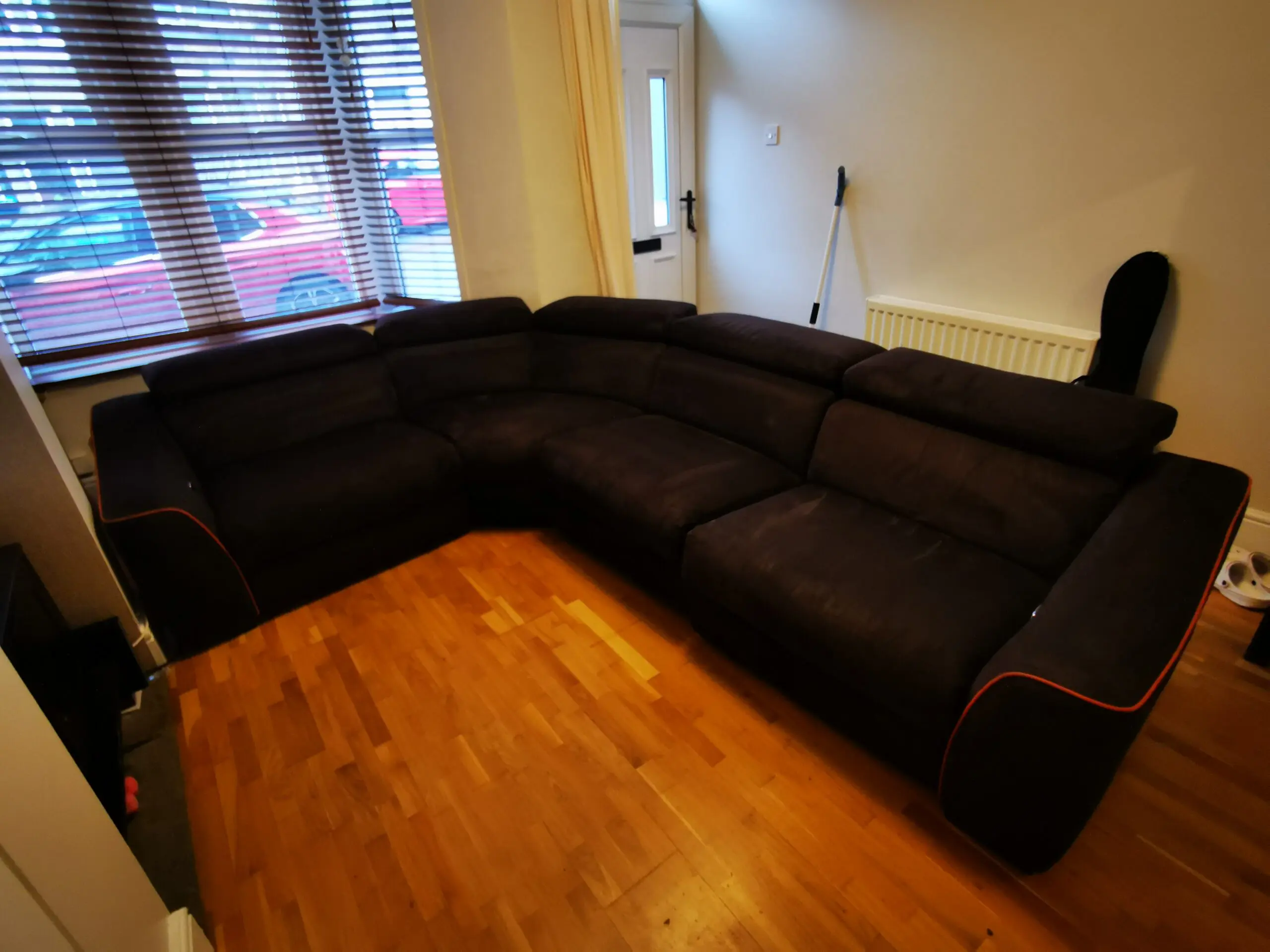 Furniture Village, corner sofa with 3 power recliner seats, black with orange piping