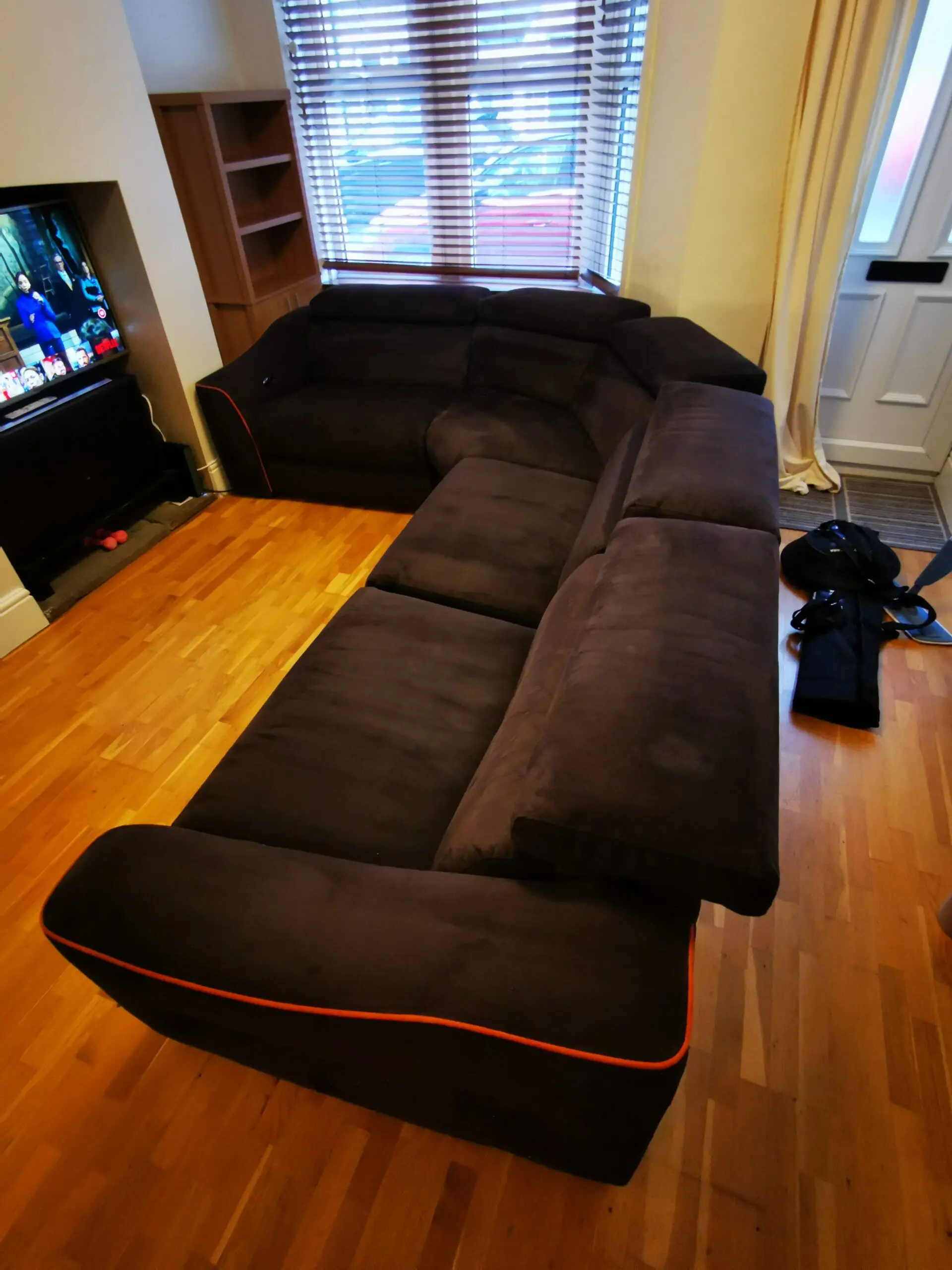 Furniture Village, corner sofa with 3 power recliner seats, black with orange piping