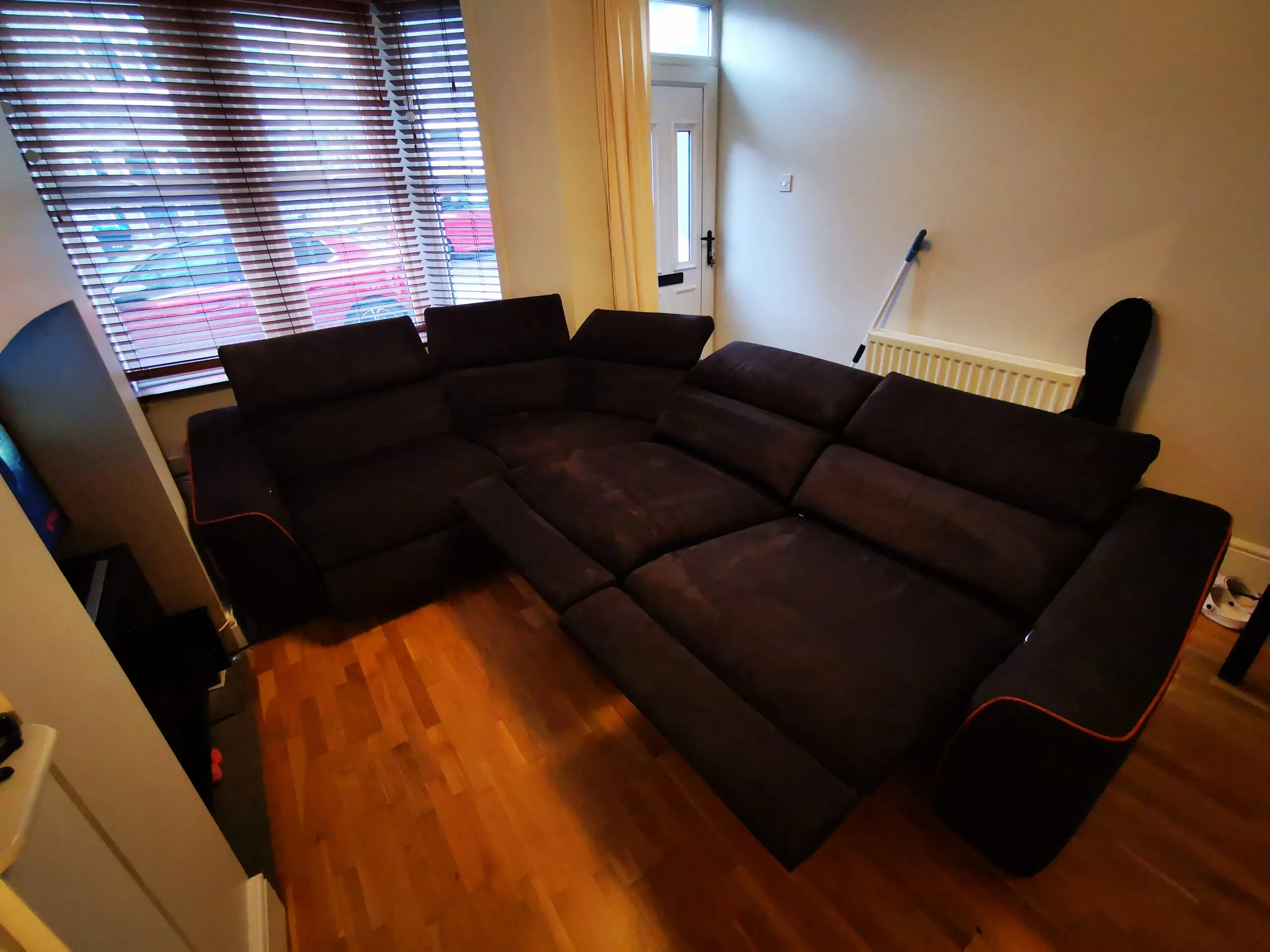 Furniture Village, corner sofa with 3 power recliner seats, black with orange piping