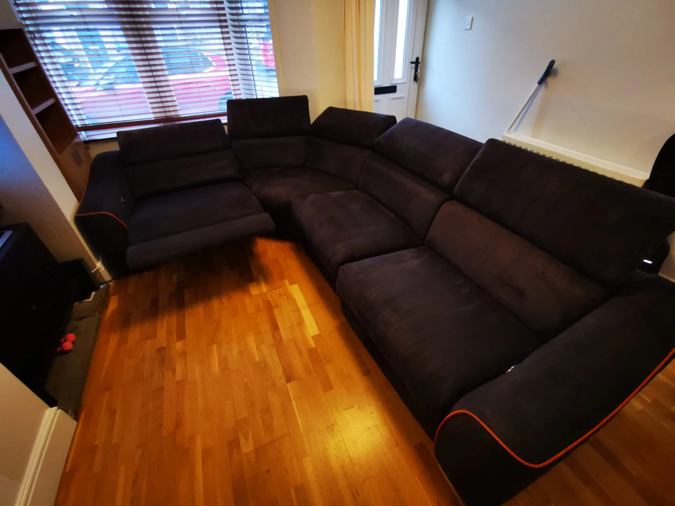 Furniture Village, corner sofa with 3 power recliner seats, black with orange piping