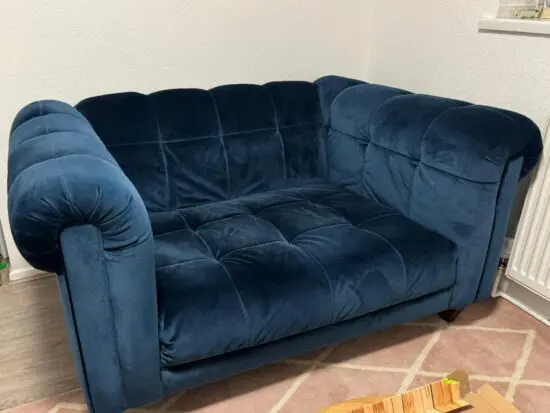 Sofology blue velvet two-seater sofa with a tufted seat, back, and arms, and dark wooden legs