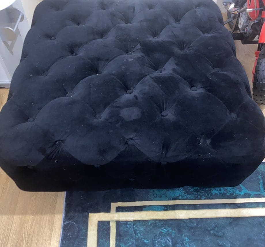 Black velvet upholstered ottoman